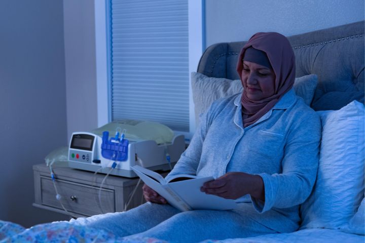 Malay dialysis patient reading beside an APD cycler machine