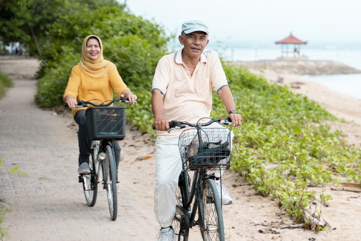 Couple with dialysis cycling on beach as exercise