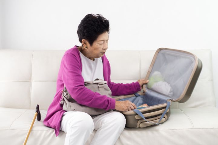 Elderly woman packing luggage to travel with dialysis